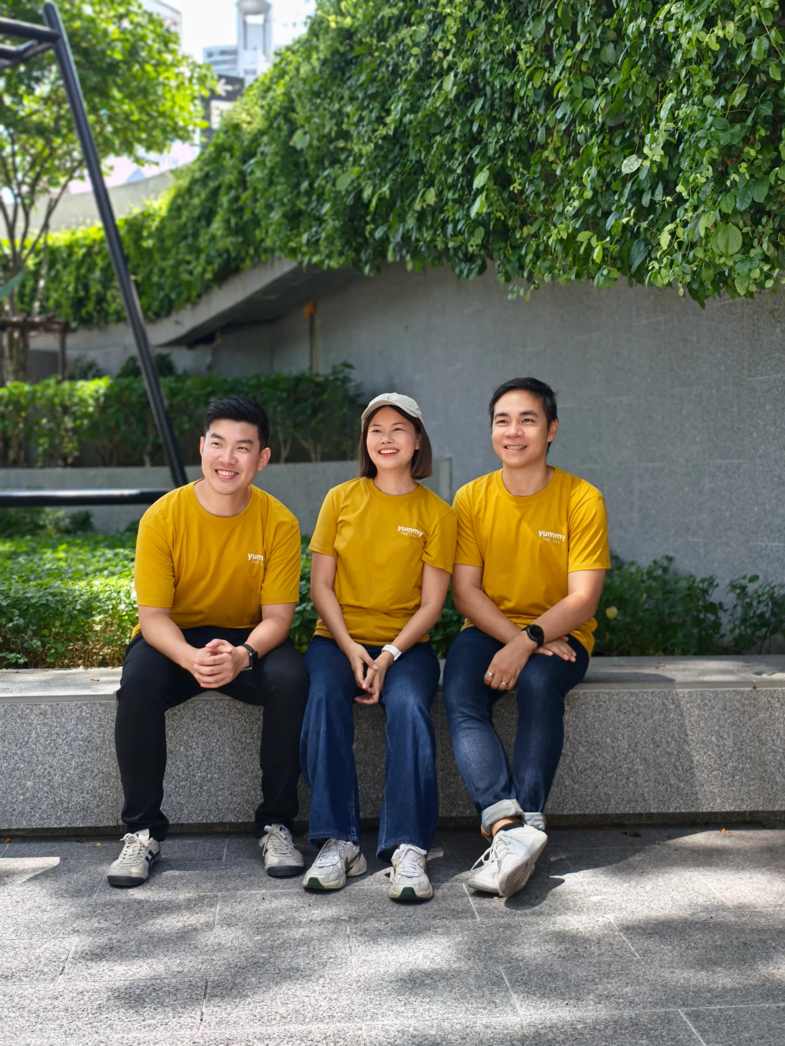 Three of the Yummy Food Tour team sitting together on a bench outside